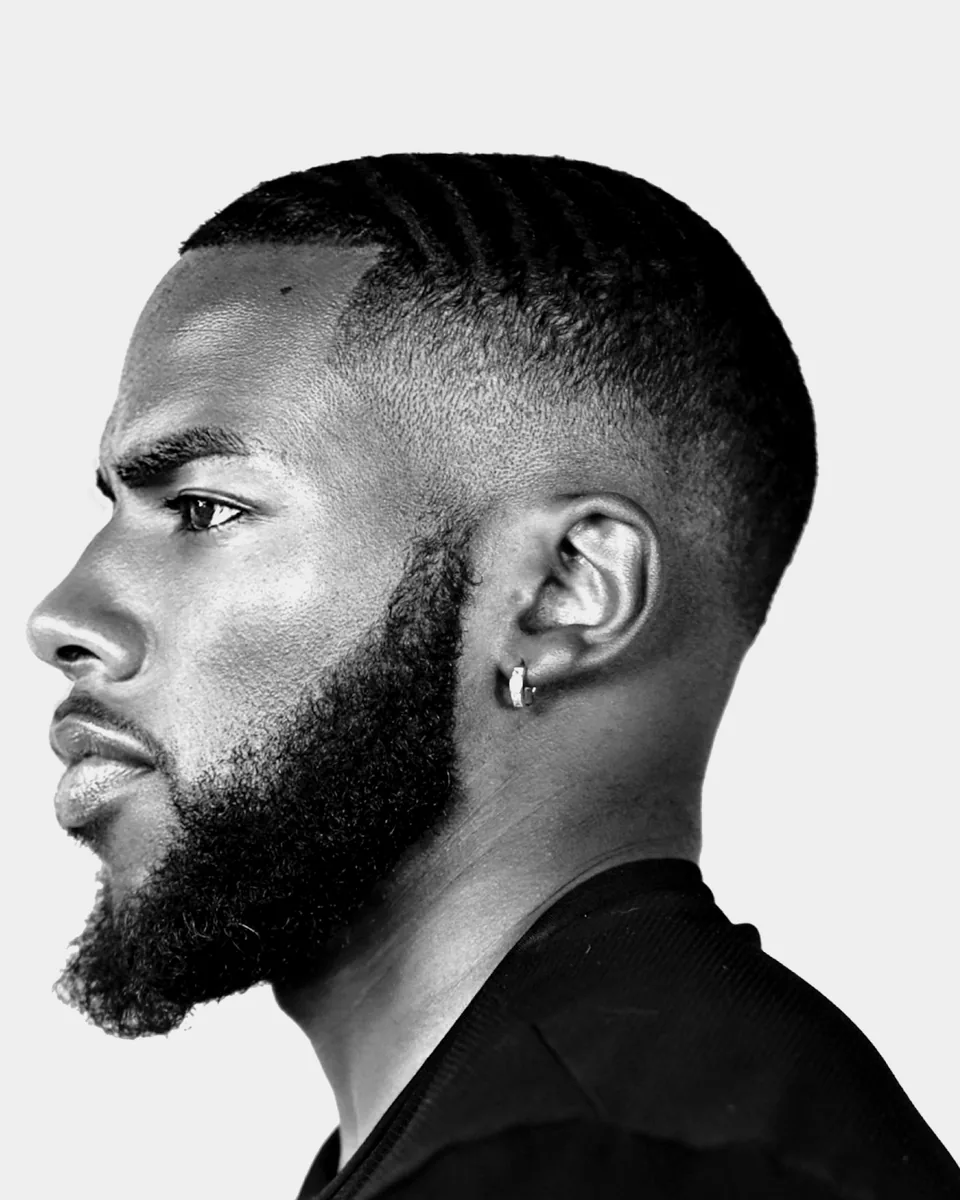 Profile of a man with a low fade, a sharp hairline and a full, shaped beard.