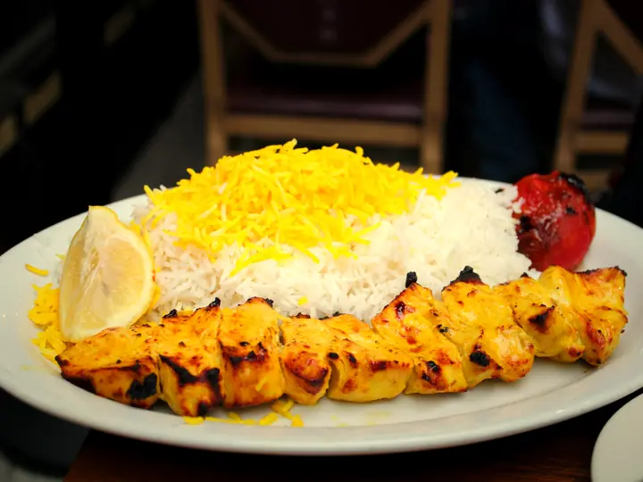 Chicken kebab on saffron rice with a grilled tomato and lemon.