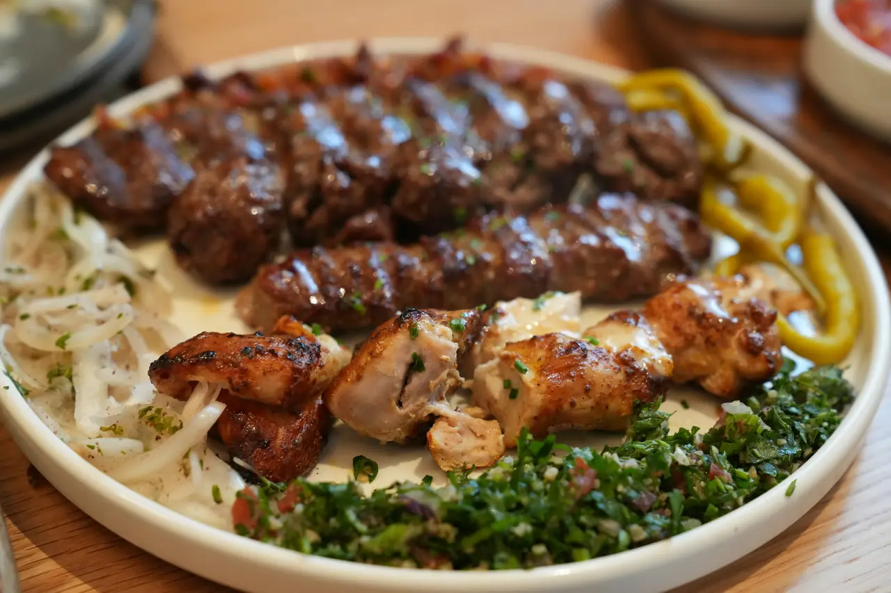 A kebab platter: two ground beef and lamb kofta skewers and chicken kebab with tabbouleh, onions and pickled peppers.