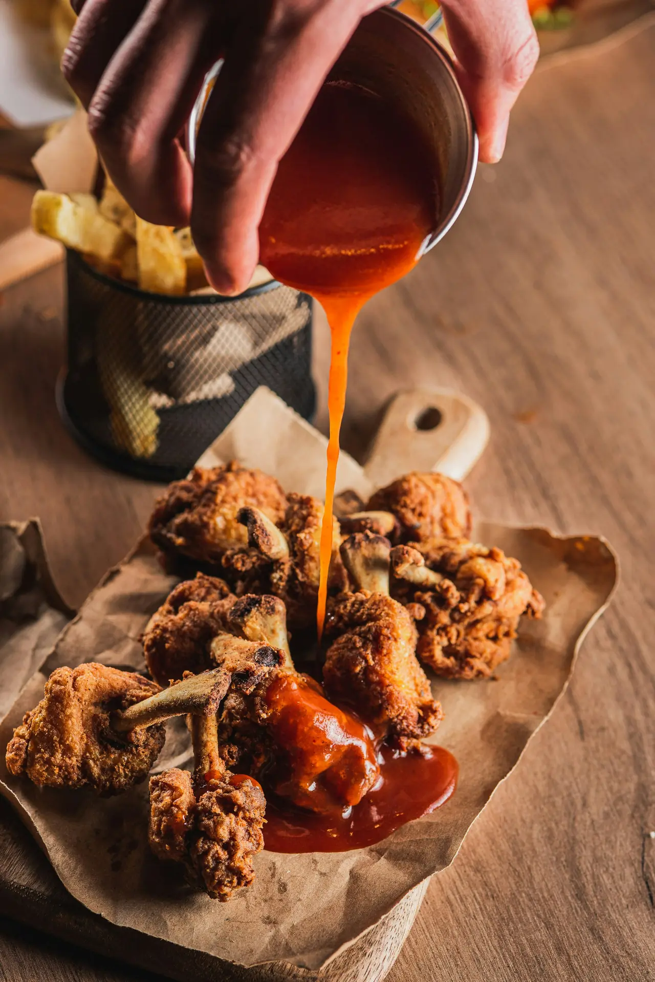 Hot sauce poured over a pile of crisp fried wings.